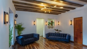 Une pièce spacieuse avec un plafond en bois, deux canapés sombres et une porte en bois.