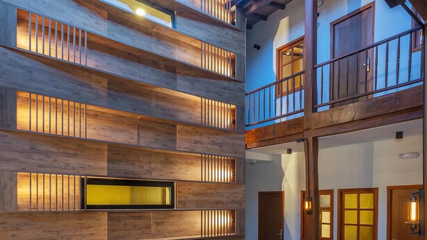 Un espace de vie extérieur moderne, doté d’un foyer, de sièges et d’un mur en bois avec un éclairage intégré.