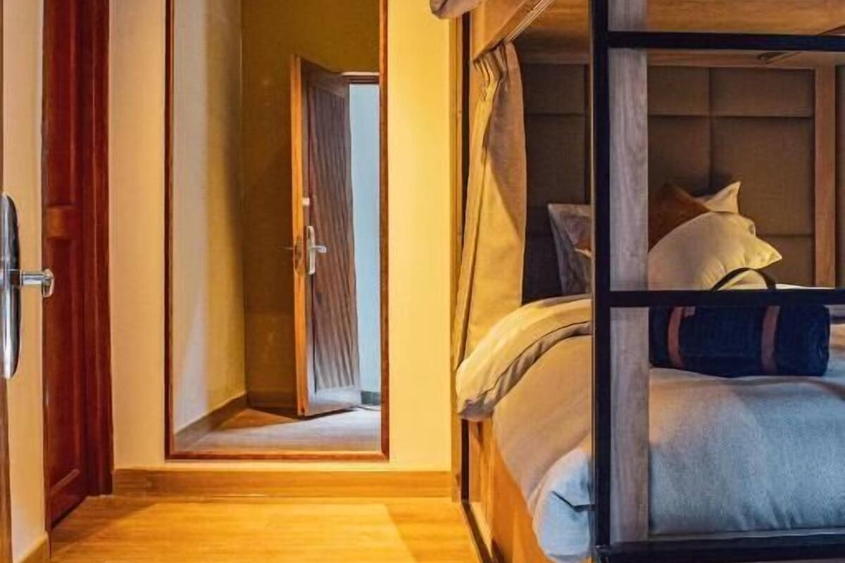 Een kamer met een stapelbed, een houten deur en een spiegel.