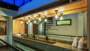 Une salle de bain moderne avec un grand miroir, un comptoir en bois et un escalier.