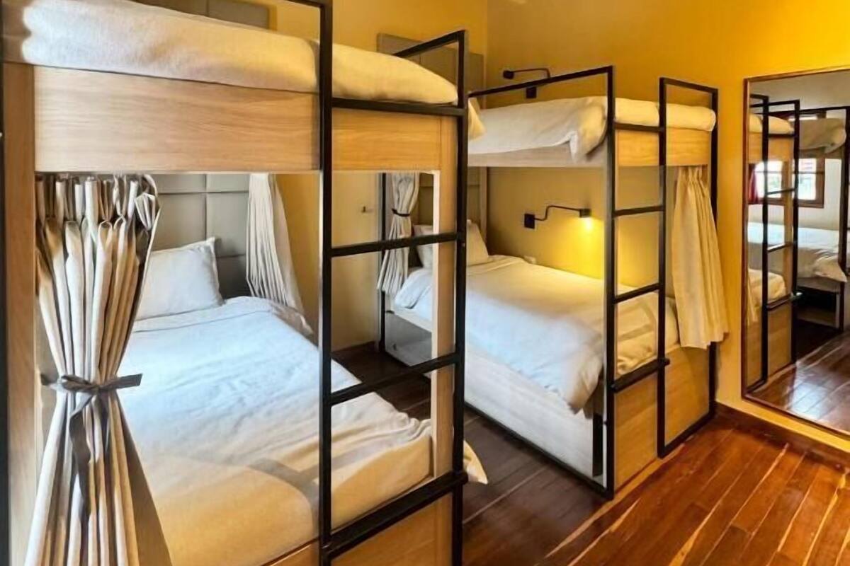 Een kamer met stapelbedden, houten vloer en een spiegel aan de muur.
