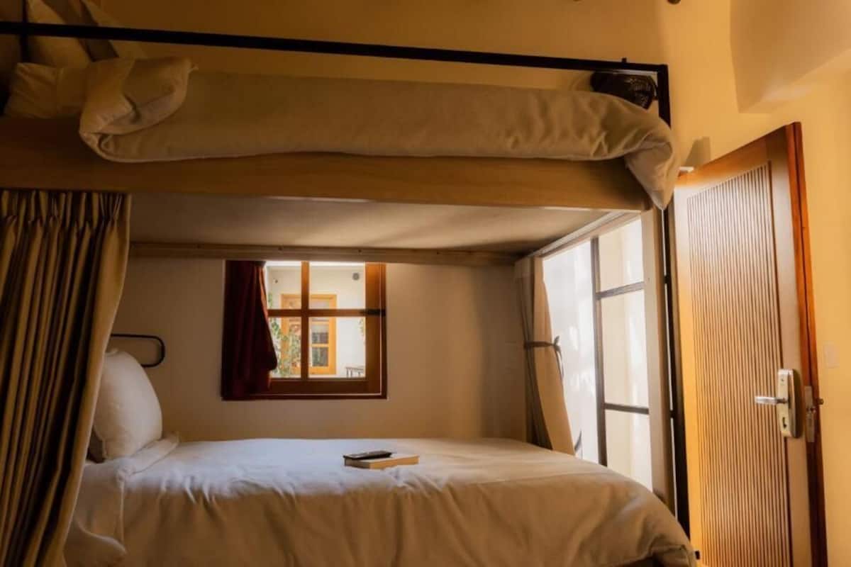 Een enkel bed met hoofdbord, een raam met gordijnen en een deur.