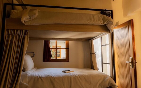 Een enkel bed met hoofdbord, een raam met gordijnen en een deur.