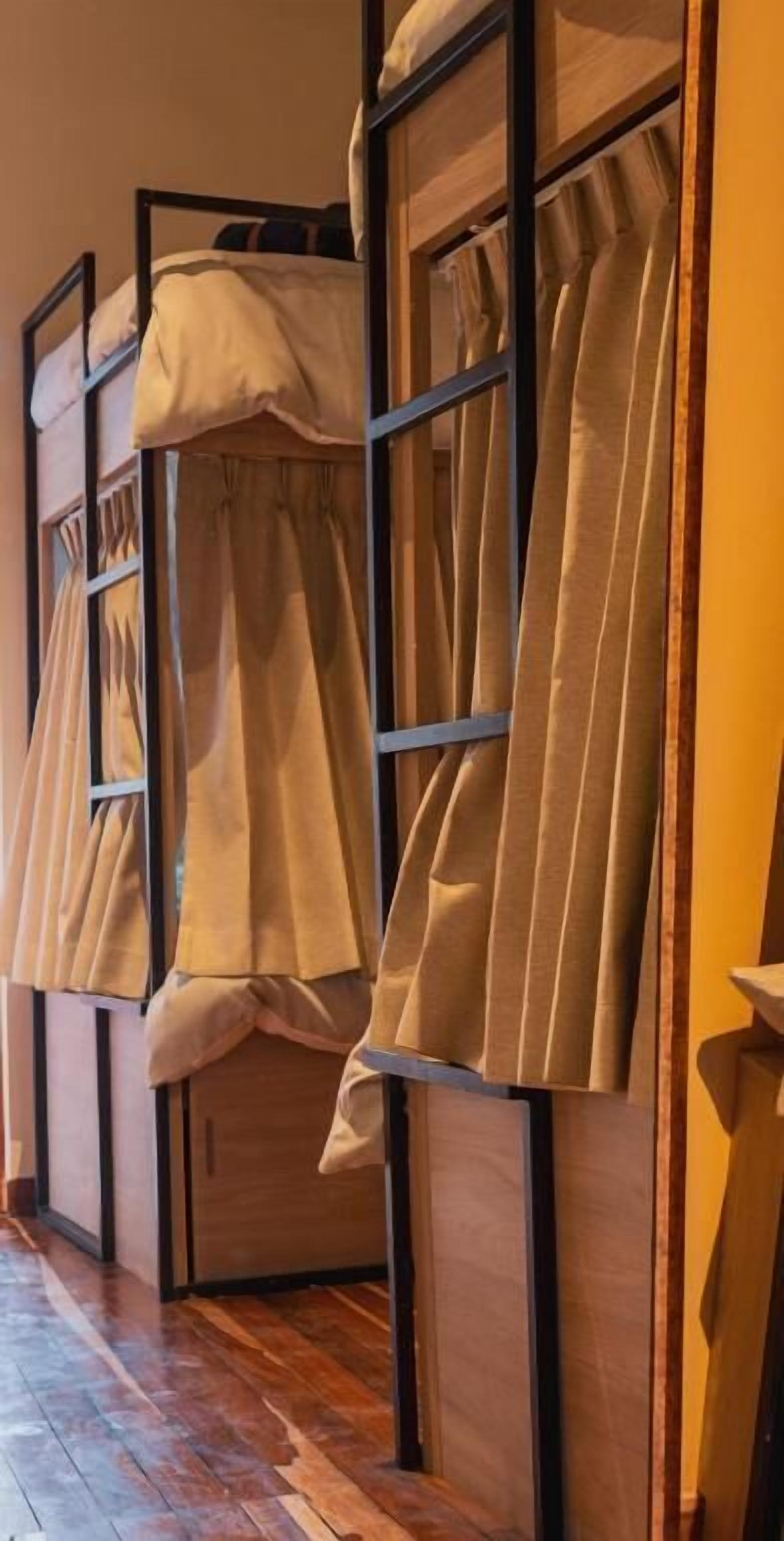 Une chambre avec un lit superposé, un plancher en bois et des rideaux.