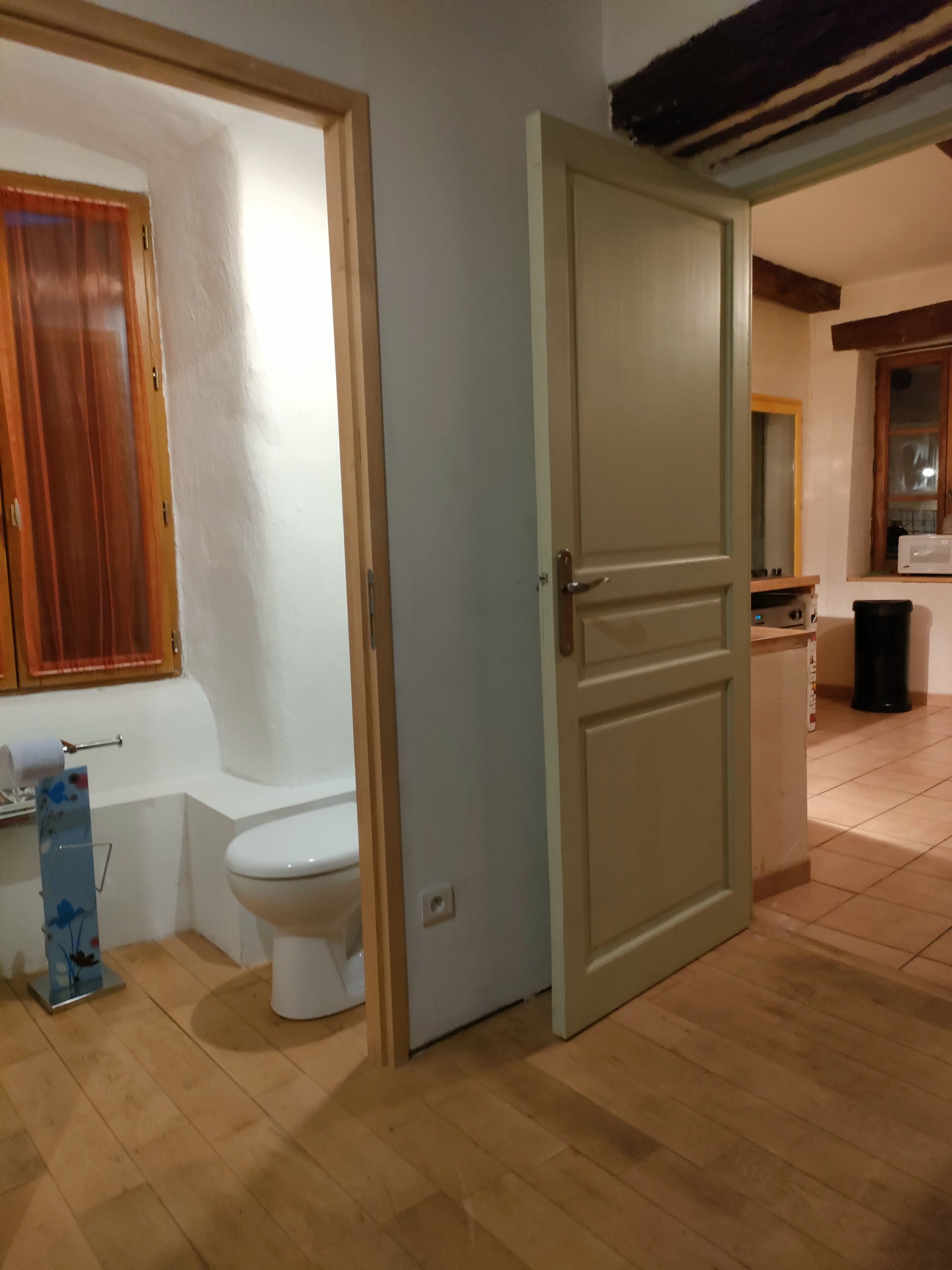 An open door leading to a bathroom with a toilet and a shower area.
