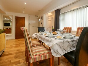 A dining area with a marble table, striped chairs, and a window with curtains. - Chickerell House (Weymouth)