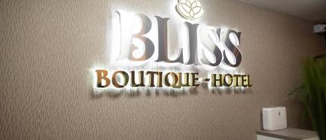 Een receptiebalie met een bordje dat 'BLISS Boutique-Hotel' vermeldt.