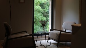 A room with a large window, a table with a vase, two chairs, and a floor lamp. - Malis Castéra Le petit château (Saint-Jean-de-Blaignac)