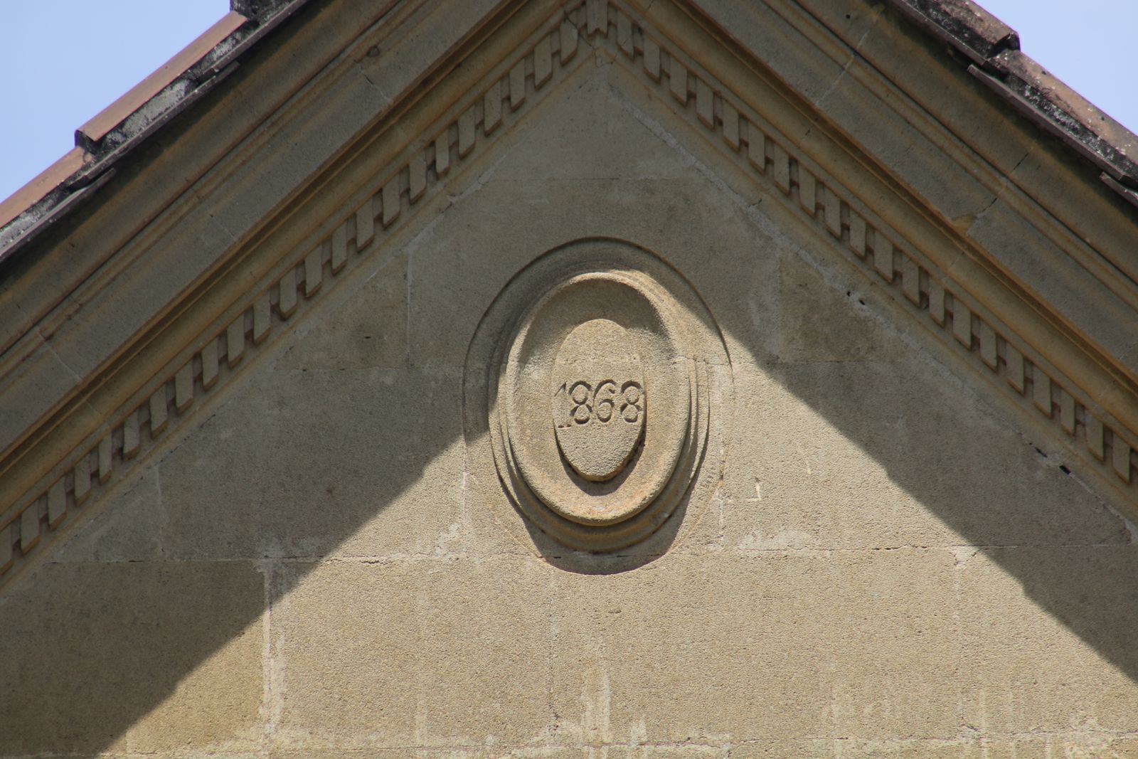 Fachada de edificio con un emblema circular que muestra el año 1868.