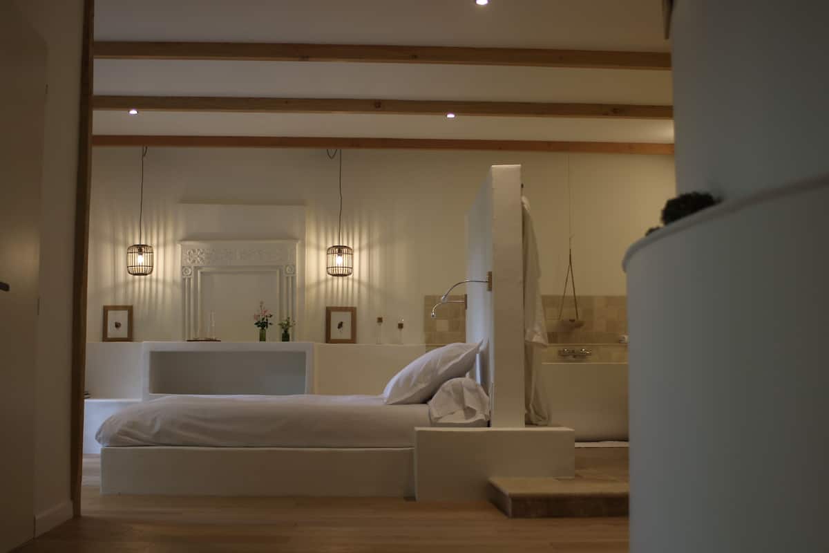 Un dormitorio moderno con una cama grande, mesitas de noche, un tocador con espejo y una zona de ducha.