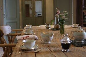 A wooden dining table with tea cups, saucers, a teapot, and a sugar bowl. - Malis Castéra Le petit château (Saint-Jean-de-Blaignac)