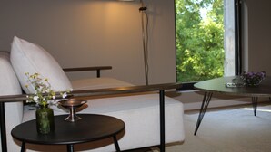 A modern living room with a sofa, a small round table with a vase and a candle, and a floor lamp. - Malis Castéra Le petit château (Saint-Jean-de-Blaignac)