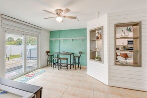 A room with a ceiling fan, a table with chairs, a sliding glass door, and a green accent wall. - Pet-Friendly Fort Pierce Home w/ Pool & Game Room! (Fort Pierce)