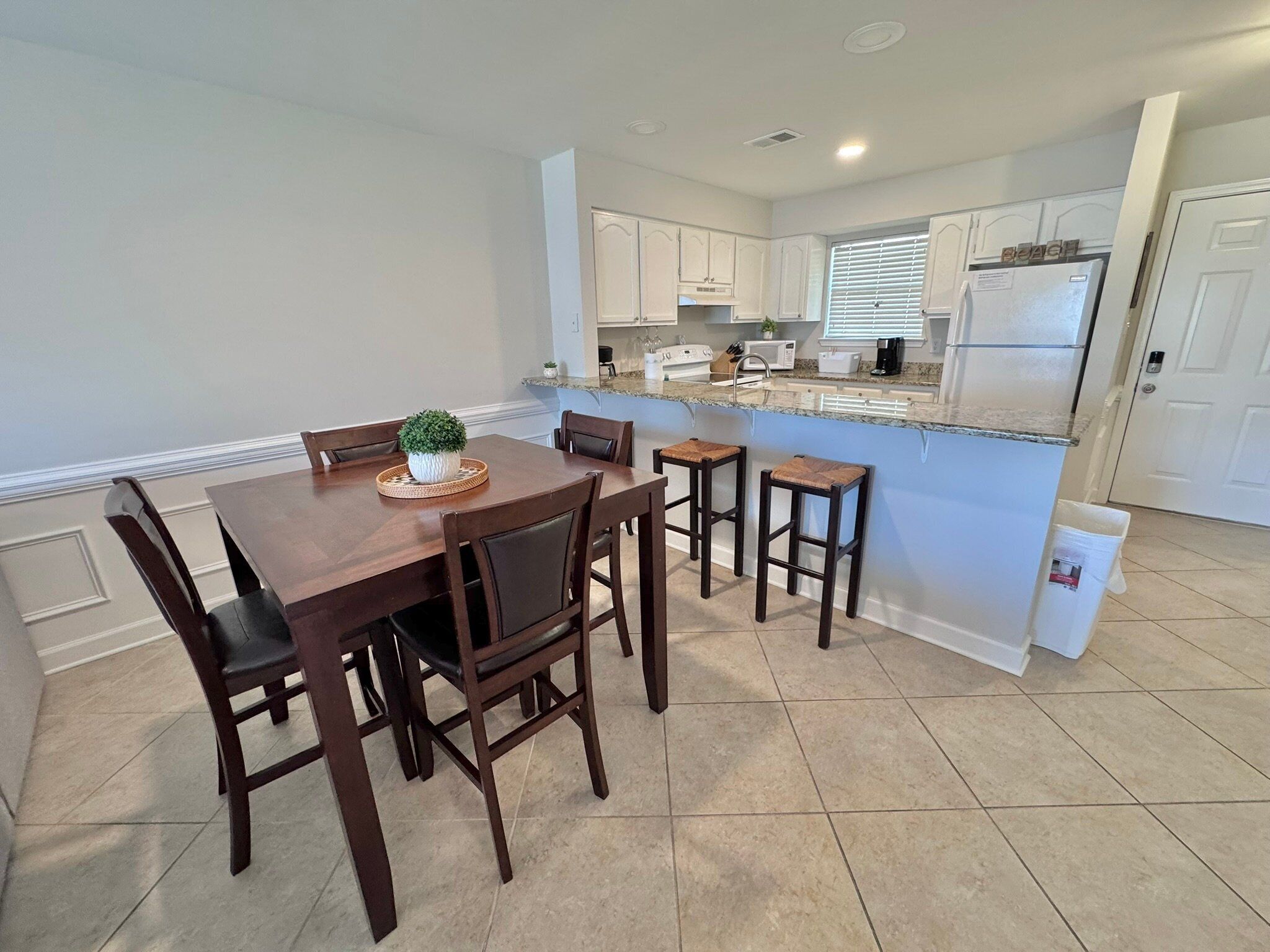 A modern kitchen with white cabinets, a granite countertop, and a built-in refrigerator.
