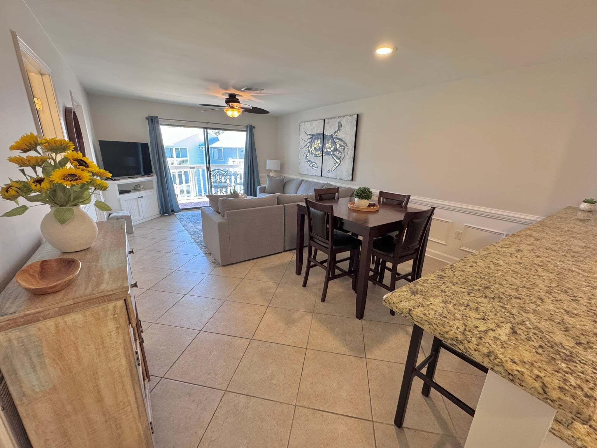 A modern kitchen with a dining area, a ceiling fan, and a view to the outside.