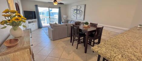 A modern kitchen with a dining area, a ceiling fan, and a view to the outside.