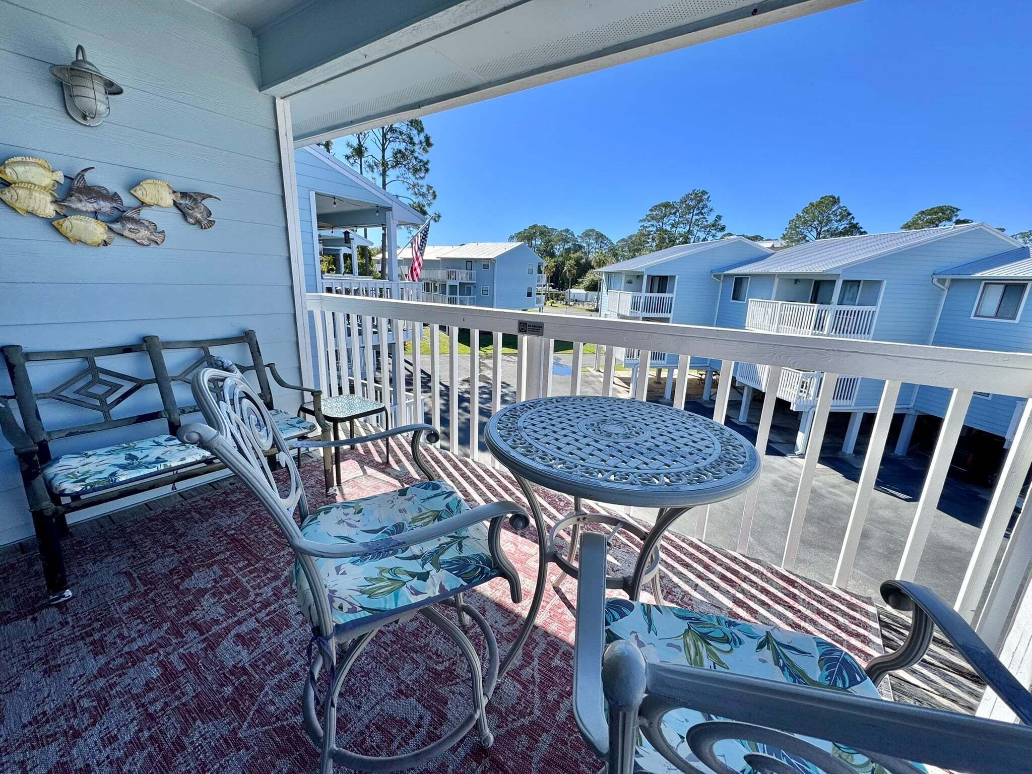 A balcony with a round table and chairs, a railing, and a view of other buildings.