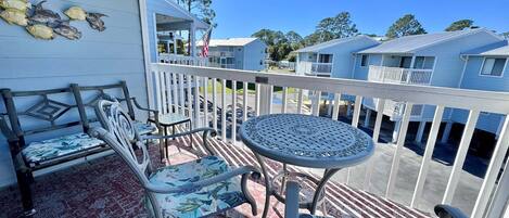 A balcony with a round table and chairs, a railing, and a view of other buildings.