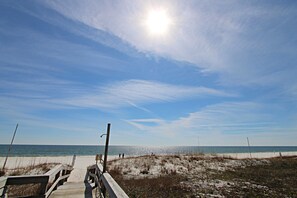 A wooden boardwalk leading to a beach with a clear sky and the sun shining. - Breakers (Orange Beach)