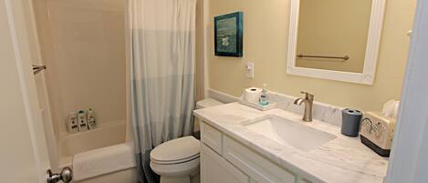 A bathroom with a shower, toilet, sink, and mirror.