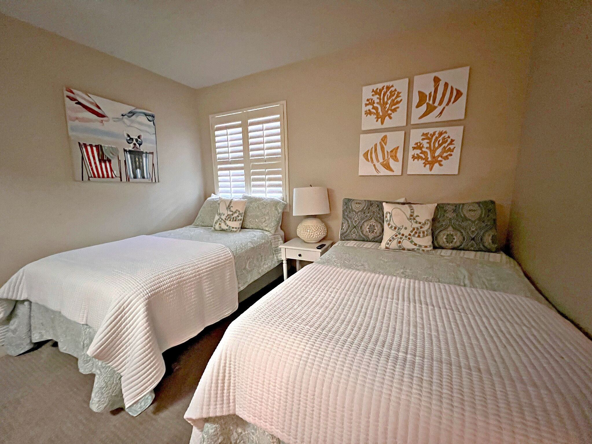 Un dormitorio con dos camas, una mesita de noche, una lámpara y decoración en la pared.