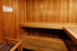 Un sauna en bois, doté de bancs et d’une étagère en métal.