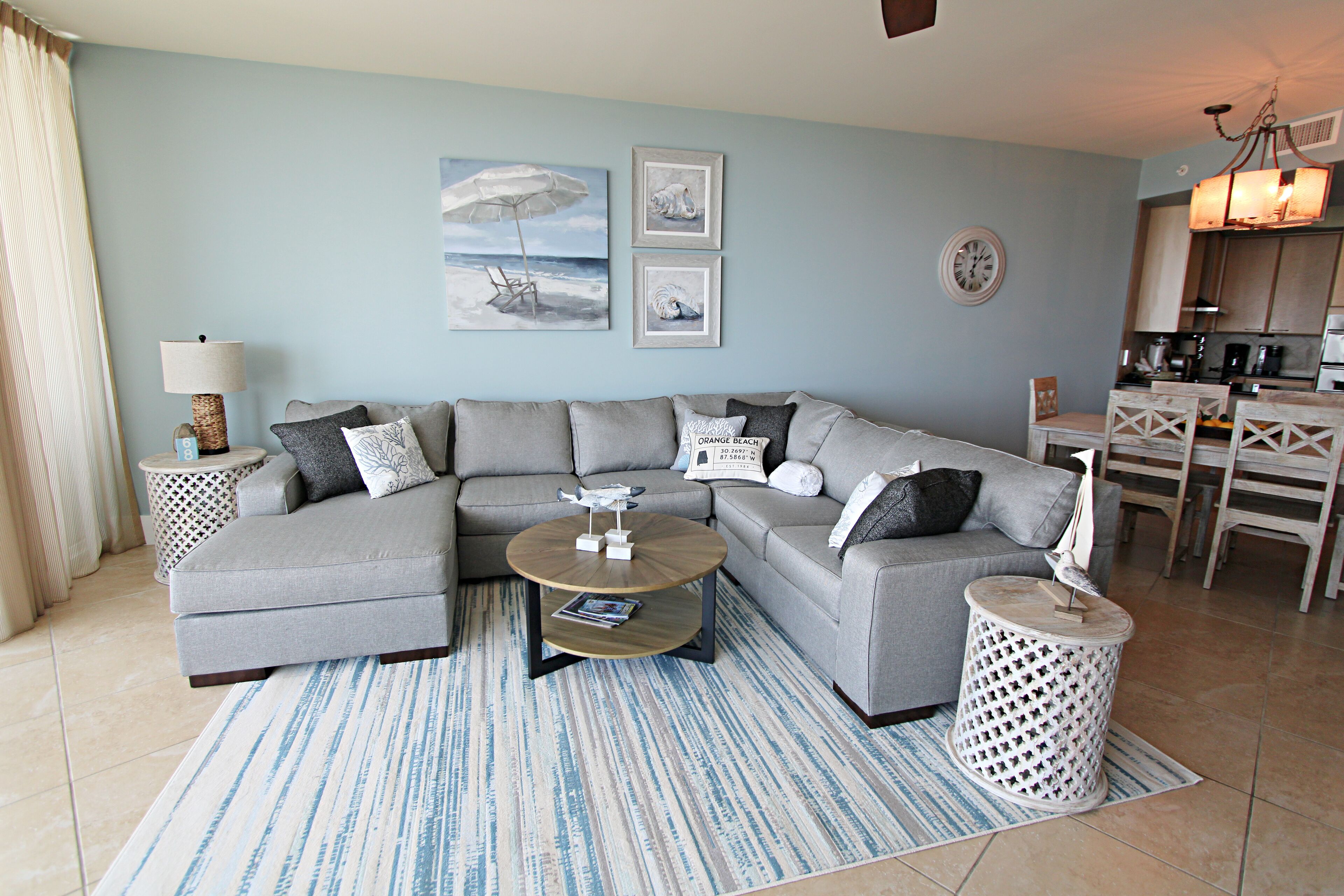 A modern living room with a sectional sofa, a coffee table, and a dining area with wooden chairs.