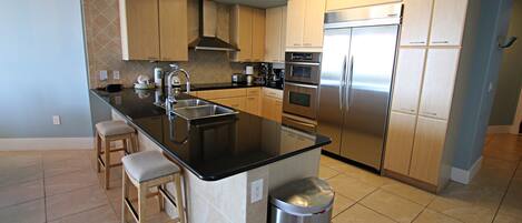 A modern kitchen with a central island, stainless steel appliances, and light wood cabinets.