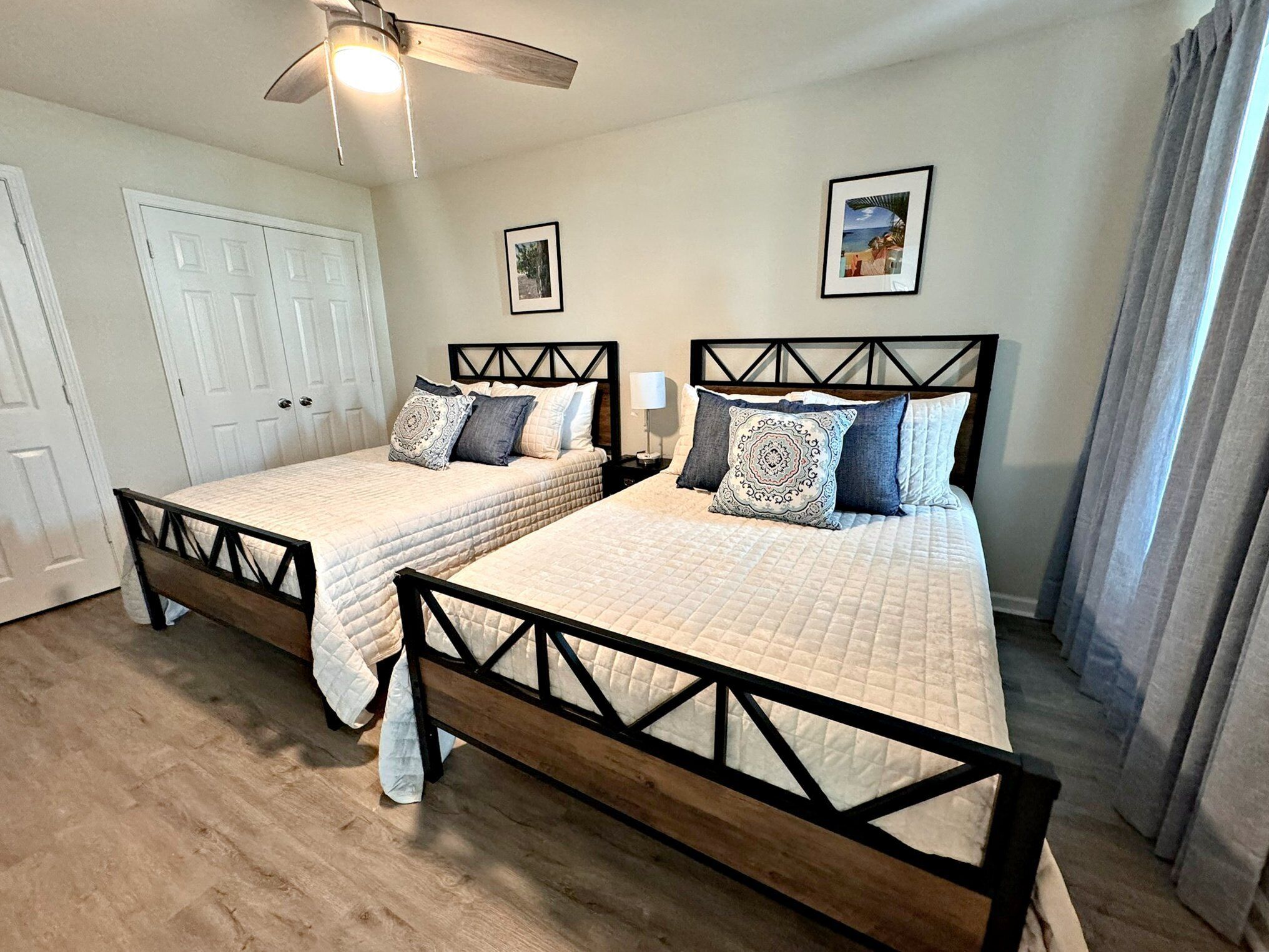 A bedroom with two beds, a ceiling fan, and a door.