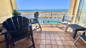 A balcony with a pool, chairs, and a view of the beach. - Driftwood Towers (Gulf Shores)