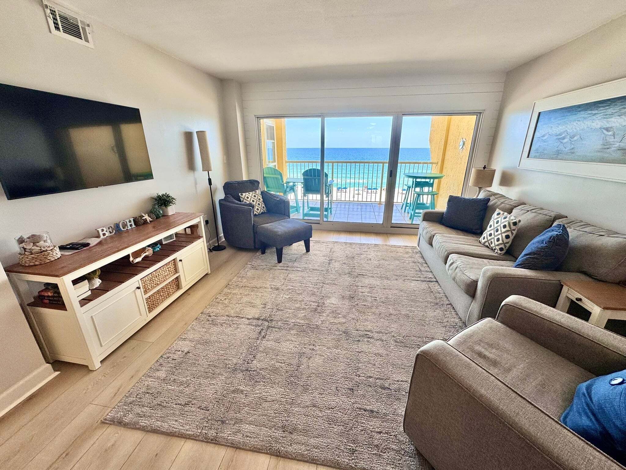 Una sala de estar con televisión de pantalla plana, un sofá, una mesa de centro y vista al océano a través de un gran ventanal corredera.