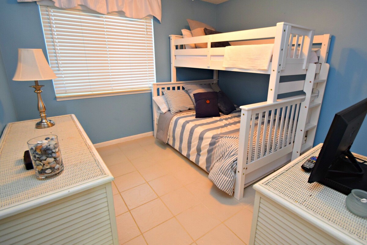 Ein Kinderzimmer mit Etagenbetten, einem Schreibtisch mit Lampe und einem Computer.
