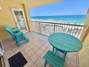 A balcony with a view of the beach, a door, and two green chairs. - Driftwood Towers (Gulf Shores)