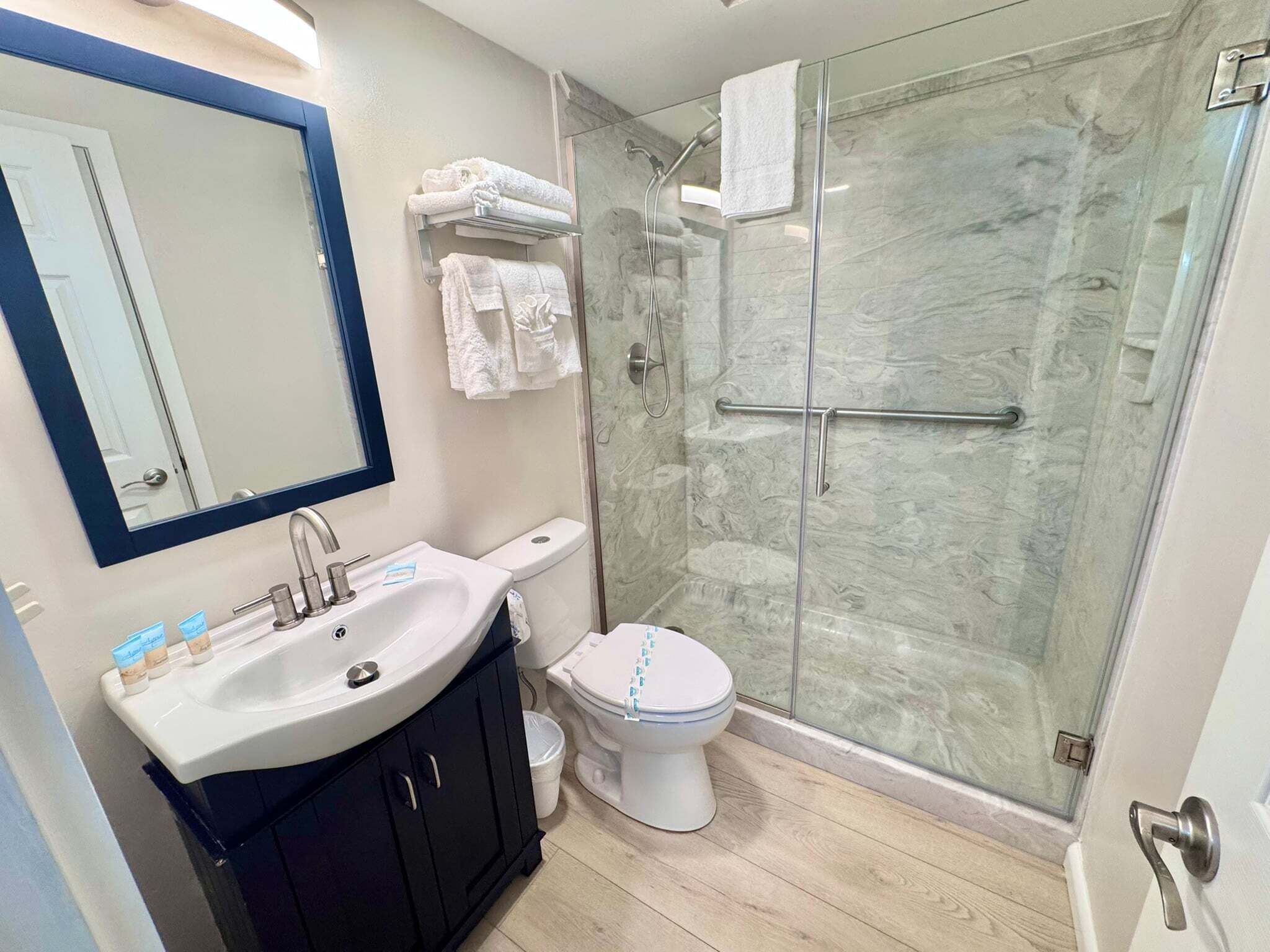 A bathroom with a sink, mirror, toilet, and glass shower enclosure.