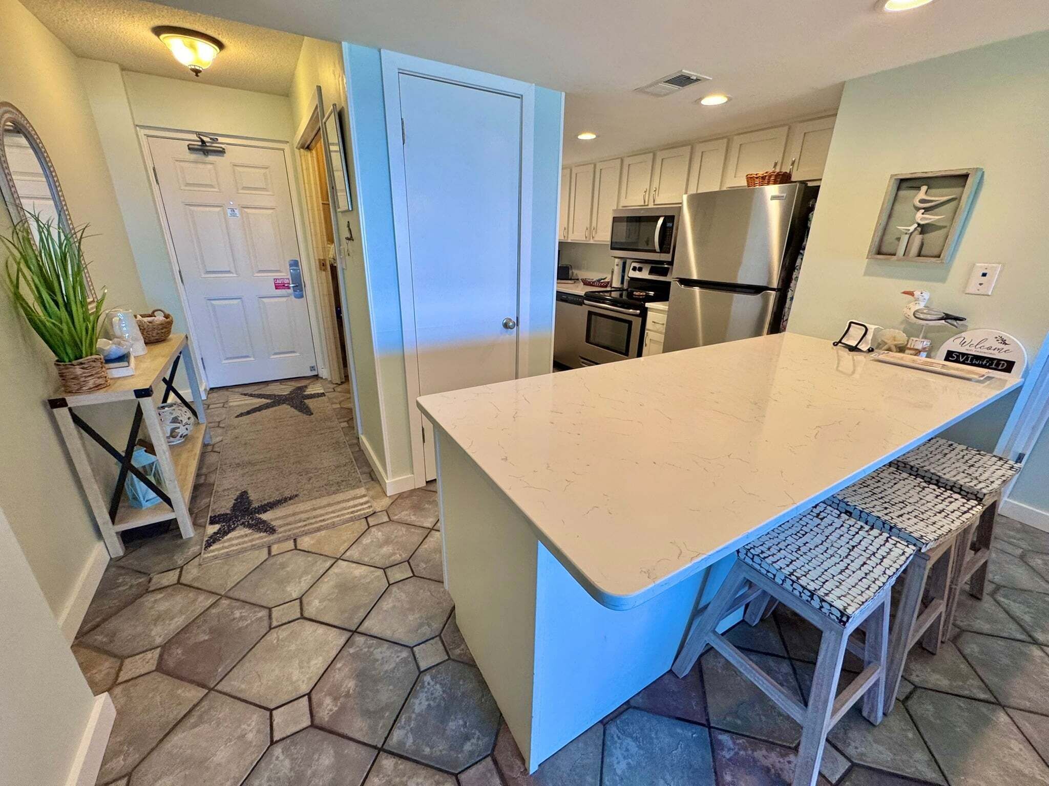 A modern kitchen with a large island, stainless steel appliances, and a tiled floor.