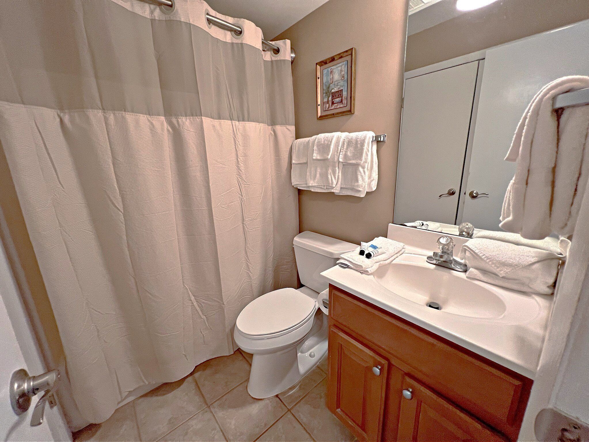 Een badkamer met toilet, wastafel en spiegel.