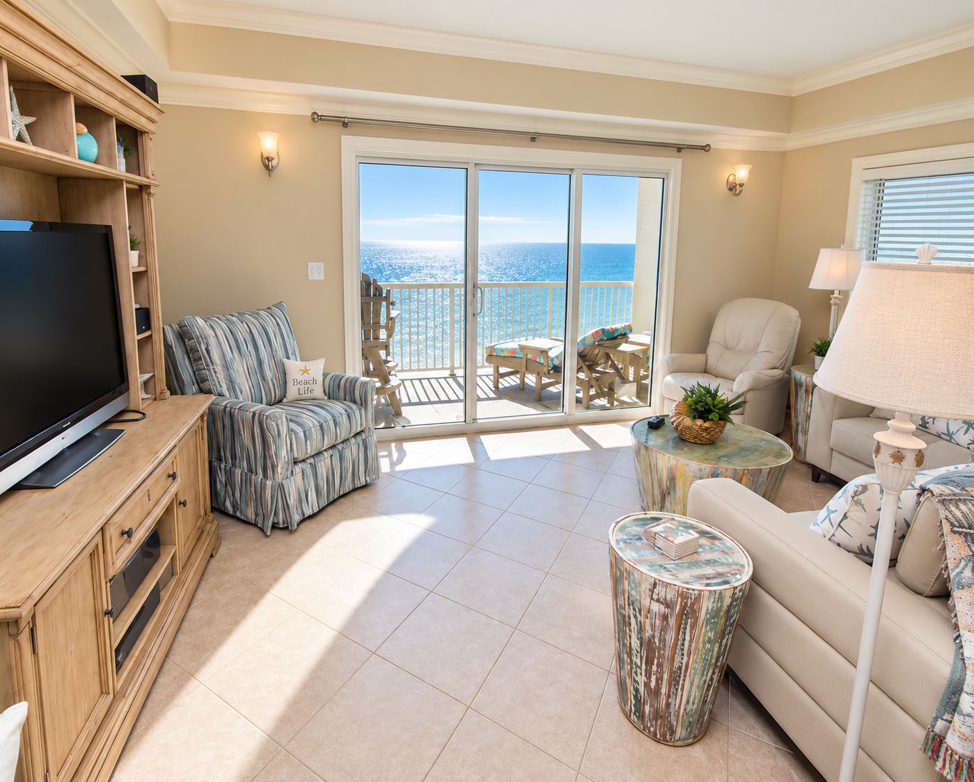 Un salon comprenant une télévision, un canapé, un fauteuil, une table basse et un balcon avec vue sur la mer.