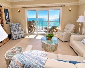 A living room with a view of the ocean, a sofa, a coffee table, and a chair. - Escapes To The Shores (Orange Beach)