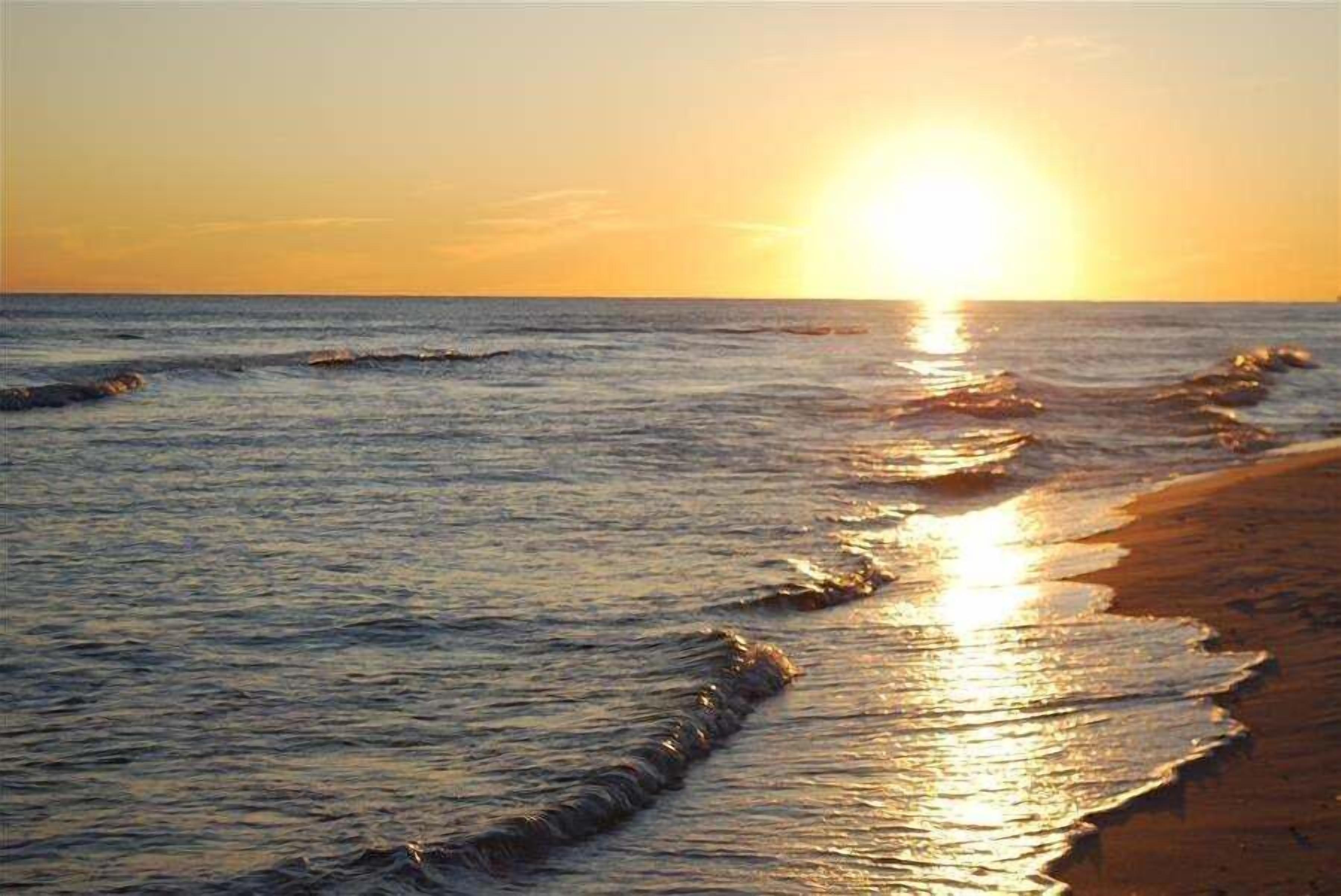 Un atardecer sobre el océano, con olas llegando a la orilla.