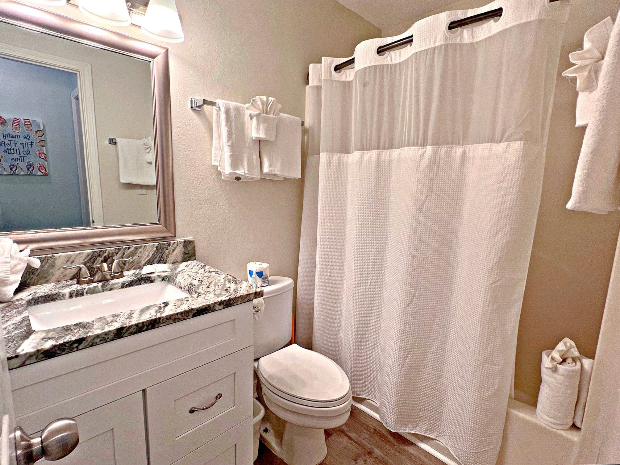 A bathroom with a marble sink, white toilet, and a shower curtain.