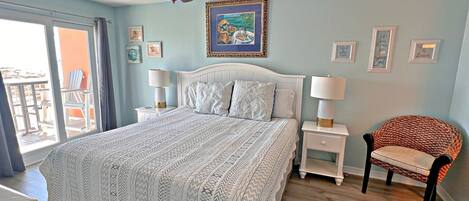 A bedroom with a large bed, two bedside tables with lamps, a ceiling fan, and a chair.