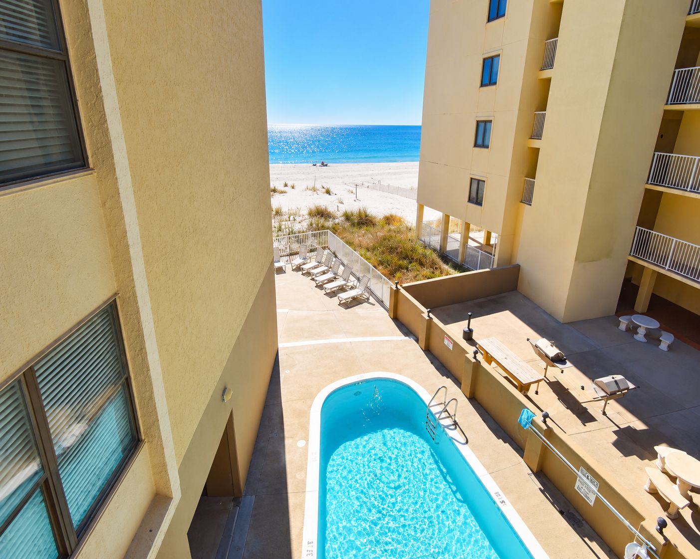 A pool area with lounge chairs and a view of the beach.