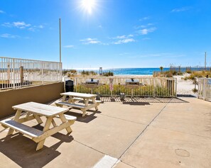 A beachside patio with picnic tables and barbecue grills, overlooking the ocean. - Gulf House (Gulf Shores)