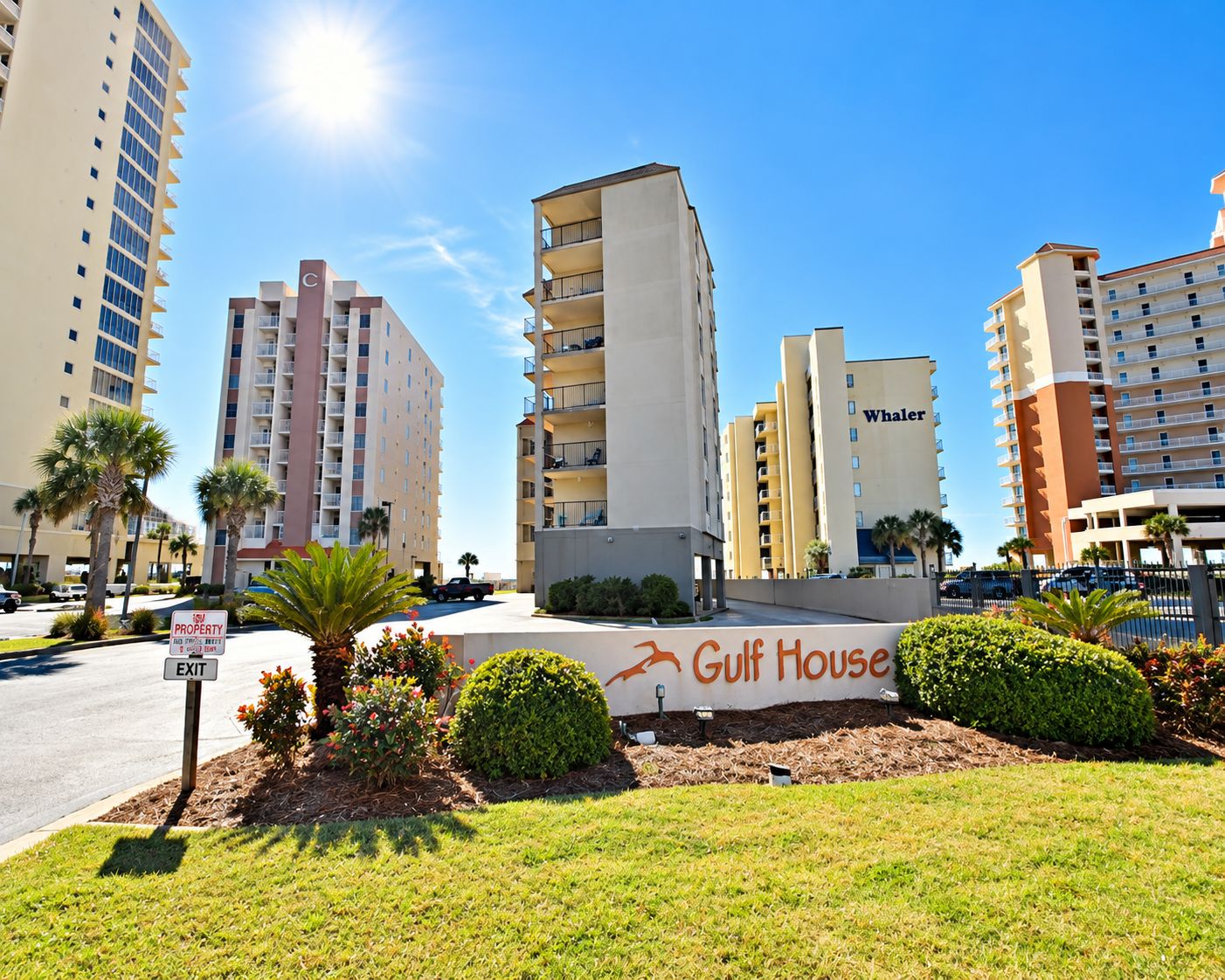 A hotel named Gulf House with a sign, surrounded by palm trees and other greenery.