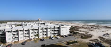 Un edificio de varios pisos con estacionamiento y vista al mar.