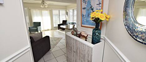 A hallway with a wooden bench, a vase with flowers, and a framed map on the wall.