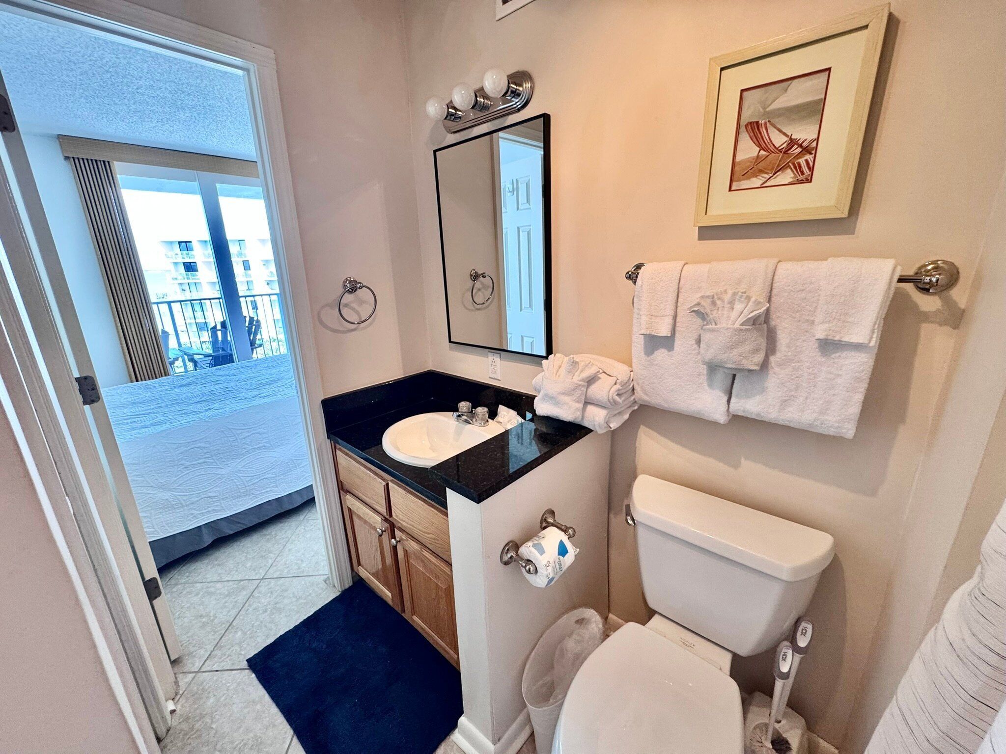 Une salle de bain équipée d’un lavabo, d’un miroir, de toilettes et de serviettes.