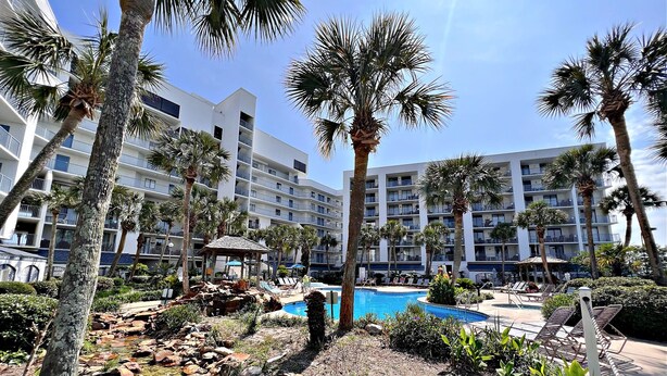A resort with a swimming pool, palm trees, and a rocky area. - Gulf Shores Surf & Racquet Club (Gulf Shores)