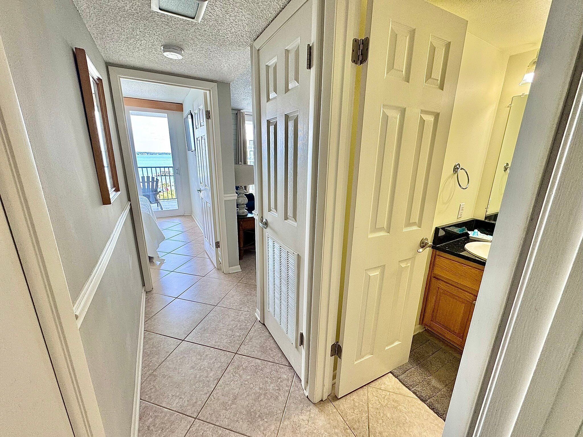 A hallway with a view to a balcony and a kitchen area.