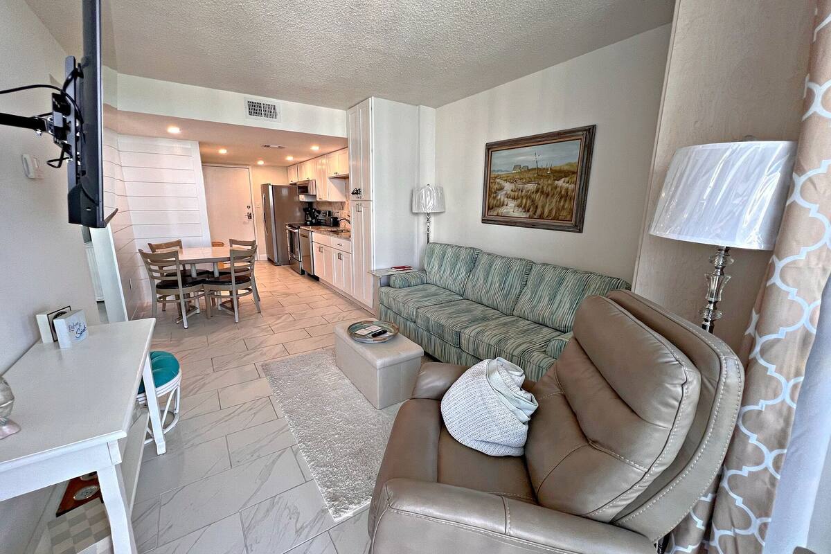 A compact living space with a dining area, kitchenette, and a sofa.